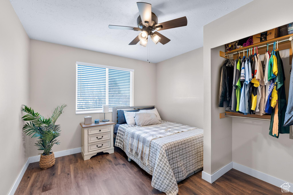 Bedroom featuring baseboards, wood finished floors, a ceiling fan, and a closet