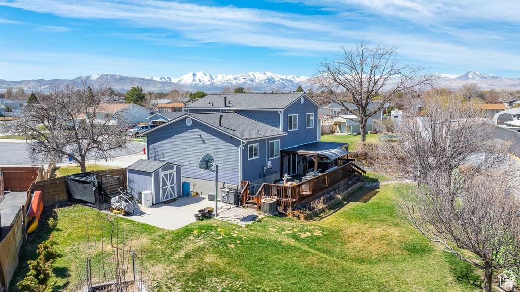 Back of house with a deck with mountain view, a residential view, and a shingled roof