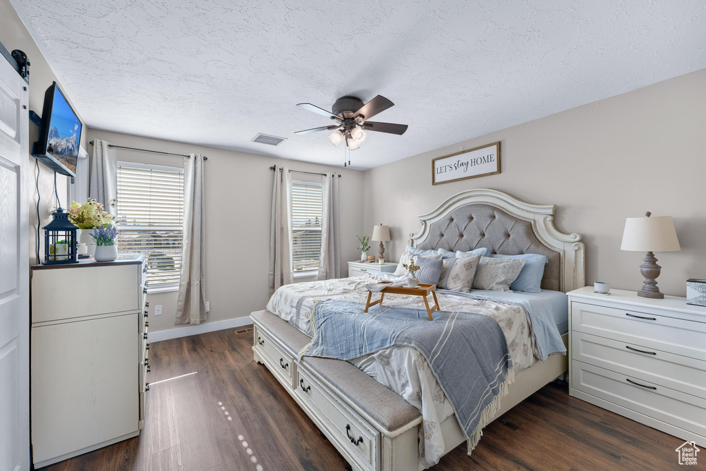 Bedroom featuring a textured ceiling, dark wood finished floors, baseboards, and a ceiling fan