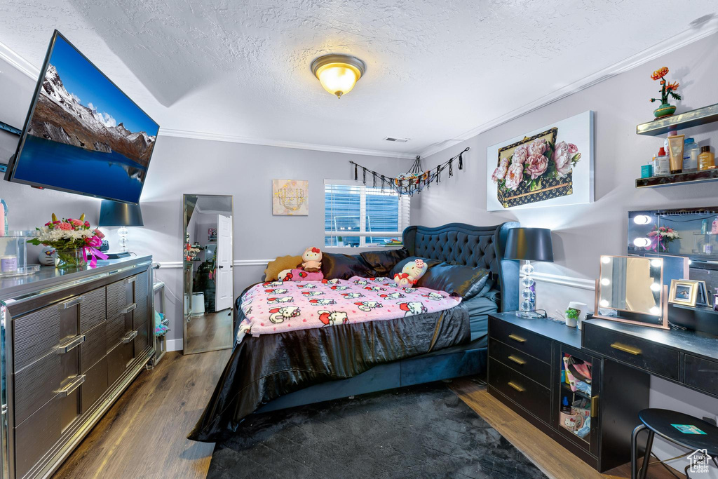 Bedroom with crown molding, a textured ceiling, and wood finished floors