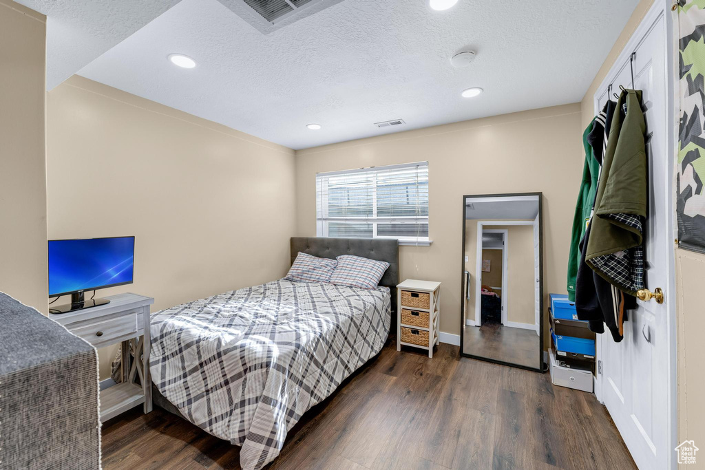 Bedroom with wood finished floors, a textured ceiling, recessed lighting, and baseboards
