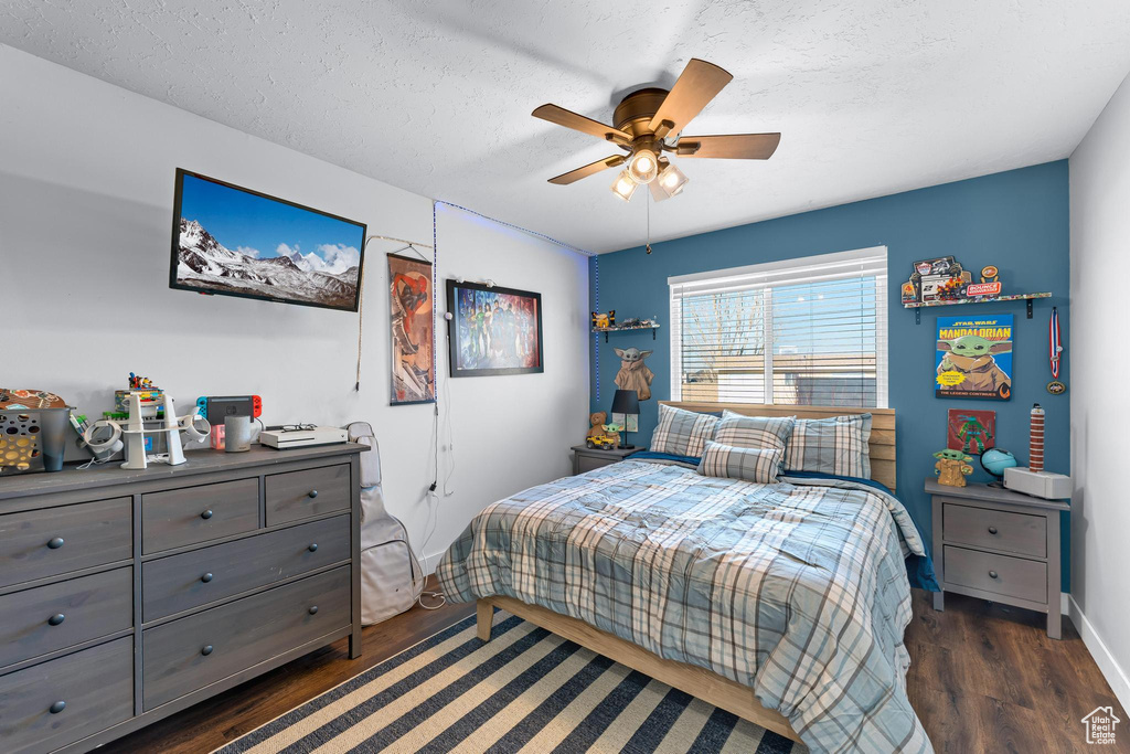 Bedroom featuring dark wood finished floors, a textured ceiling, baseboards, and ceiling fan