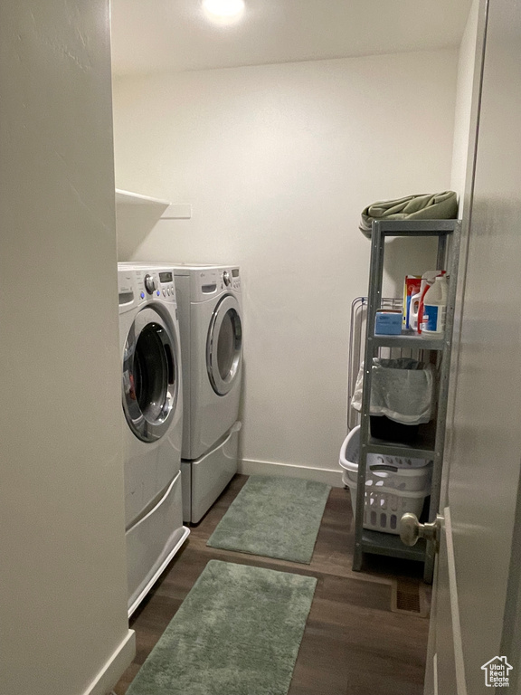 Laundry room featuring separate washer and dryer, baseboards, and dark wood finished floors