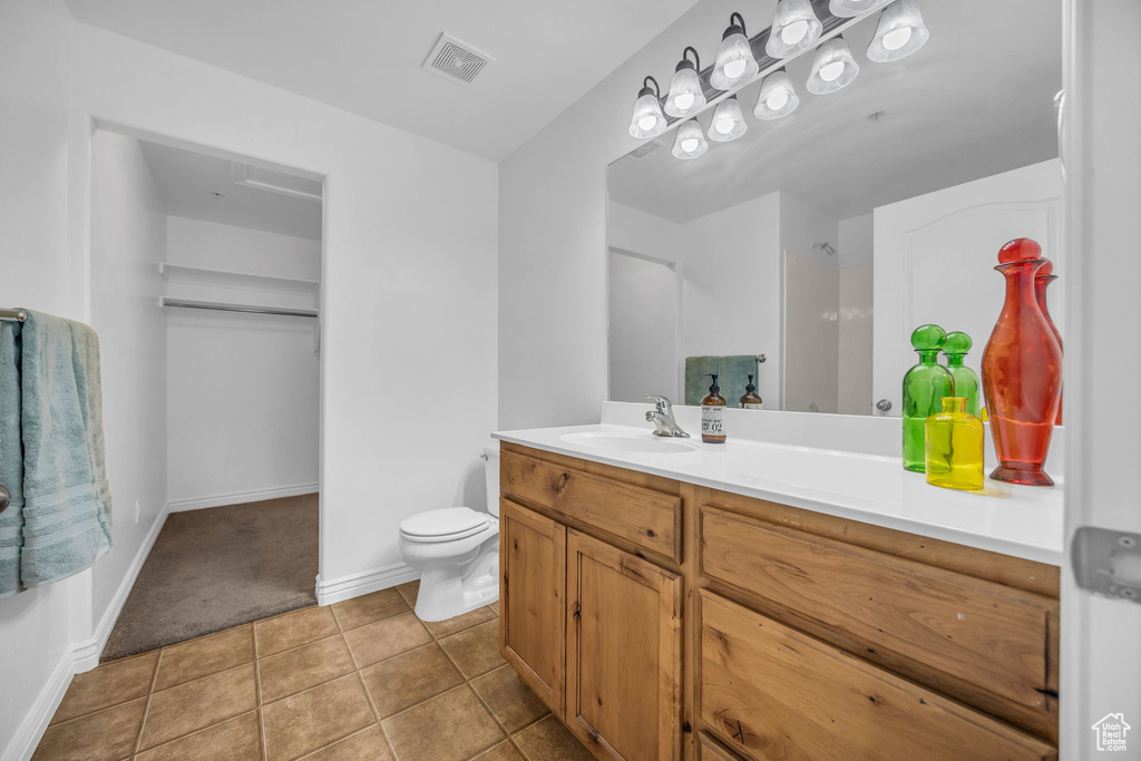 Bathroom featuring vanity, toilet, tile patterned flooring, and baseboards