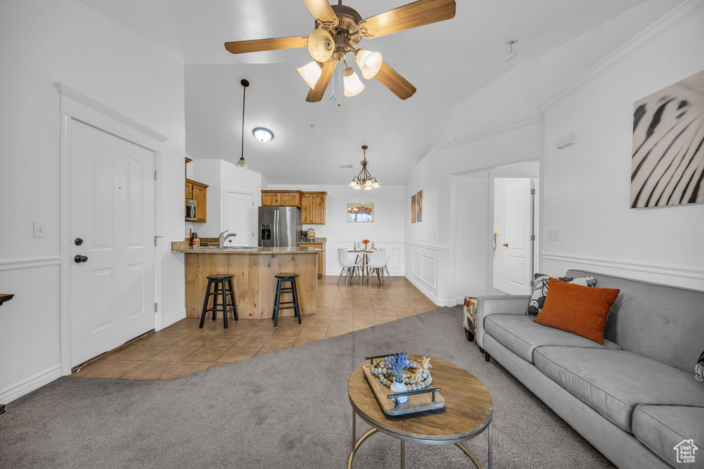 Living area featuring light tile patterned flooring, light colored carpet, ceiling fan, high vaulted ceiling, and a chandelier