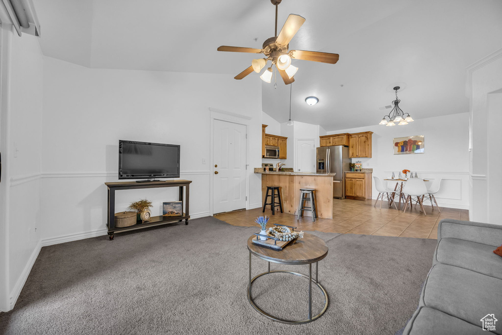 Living room with a ceiling fan, a chandelier, high vaulted ceiling, light colored carpet, and light tile patterned flooring