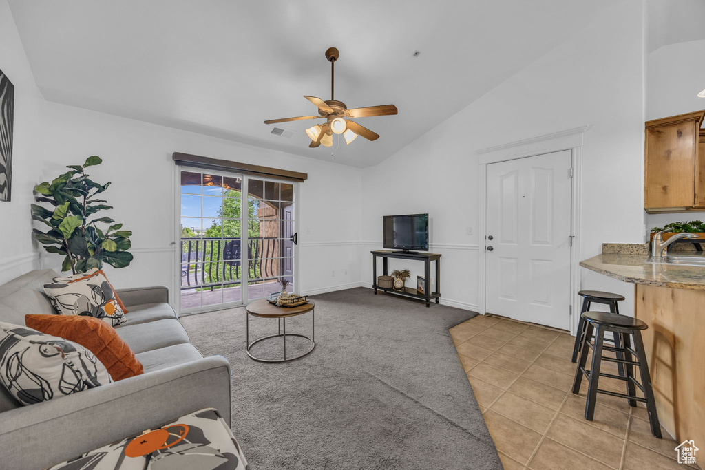 Living room with ceiling fan, light tile patterned flooring, high vaulted ceiling, and light colored carpet