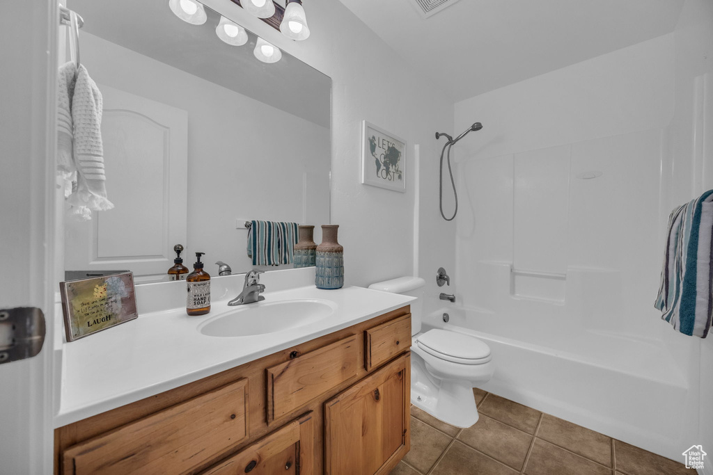 Full bath featuring vanity, washtub / shower combination, tile patterned flooring, and toilet