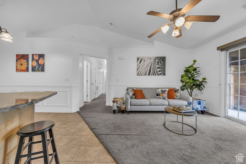 Living area with lofted ceiling, light carpet, plenty of natural light, a ceiling fan, and light tile patterned flooring