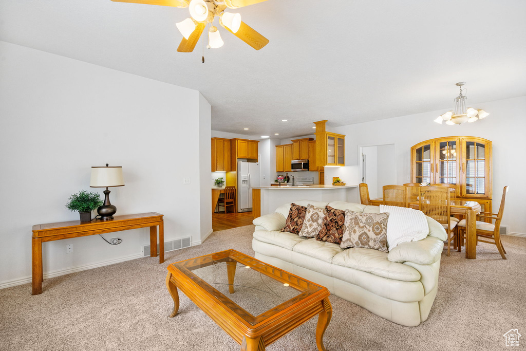 Living room featuring light colored carpet, a chandelier, a ceiling fan, baseboards, and recessed lighting