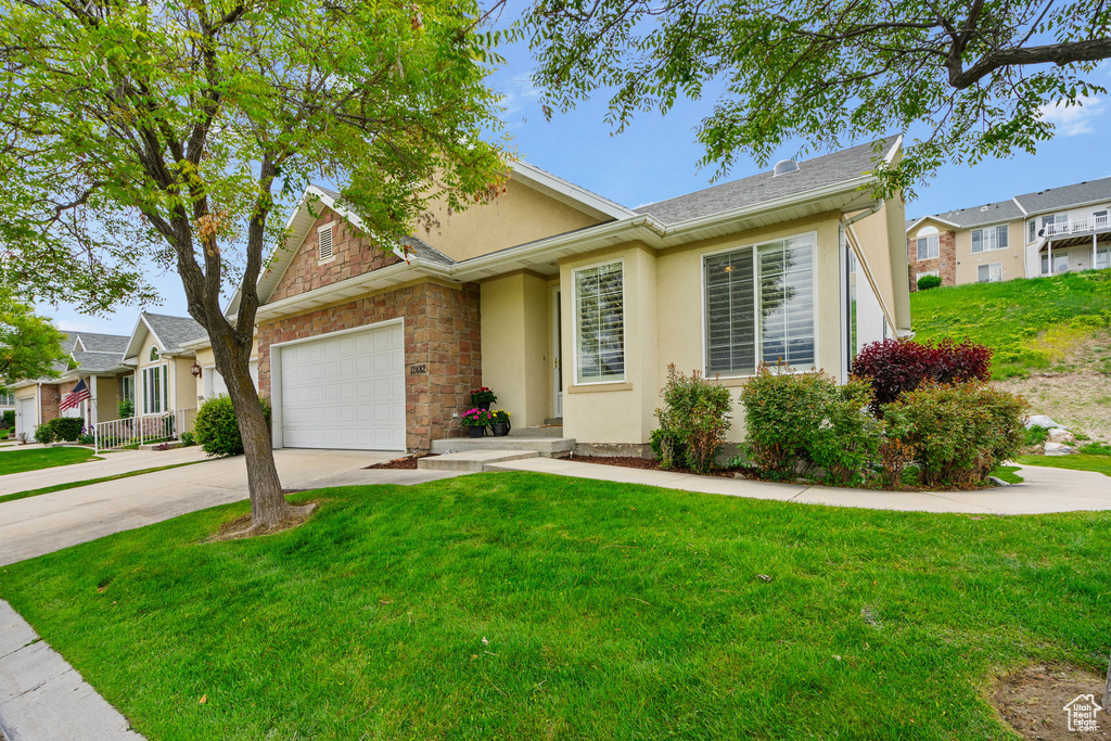 View of front of property with stucco siding, concrete driveway, an attached garage, a front yard, and a residential view