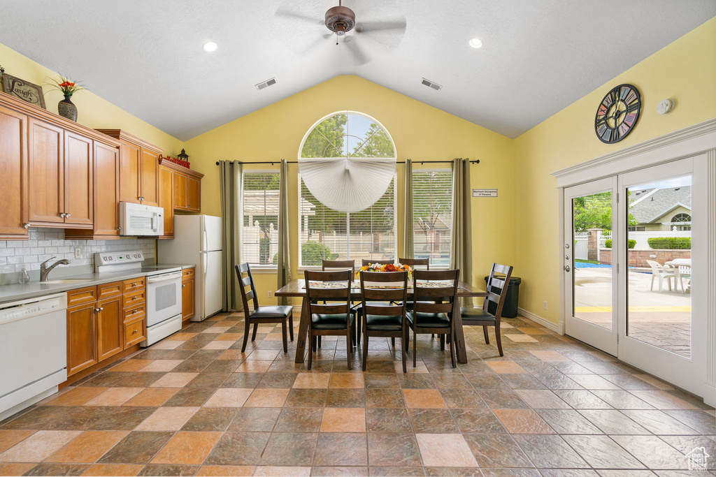 Kitchen with white appliances, ceiling fan, lofted ceiling, healthy amount of natural light, and stone tile flooring