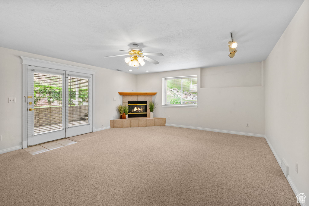 Unfurnished living room featuring carpet, ceiling fan, a fireplace, and baseboards
