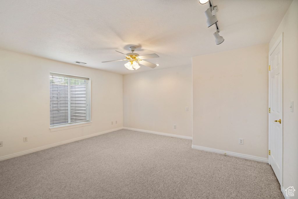 Spare room with ceiling fan, light carpet, and baseboards