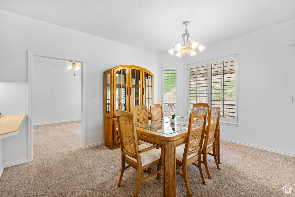 Dining room featuring light colored carpet, a chandelier, plenty of natural light, and baseboards