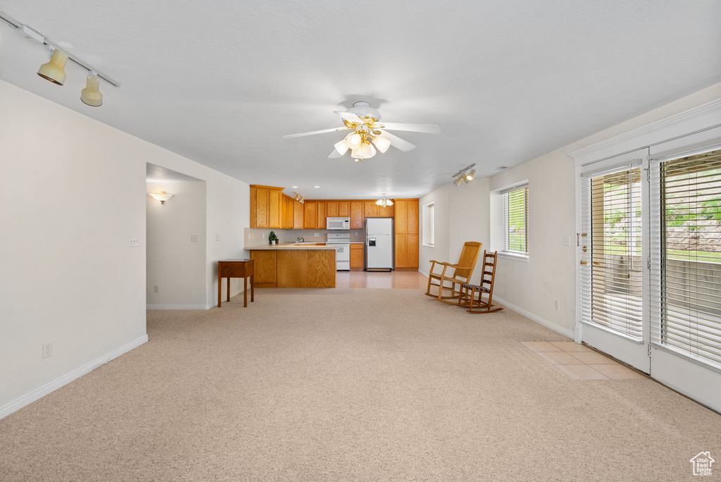 Living room with ceiling fan, light carpet, and baseboards