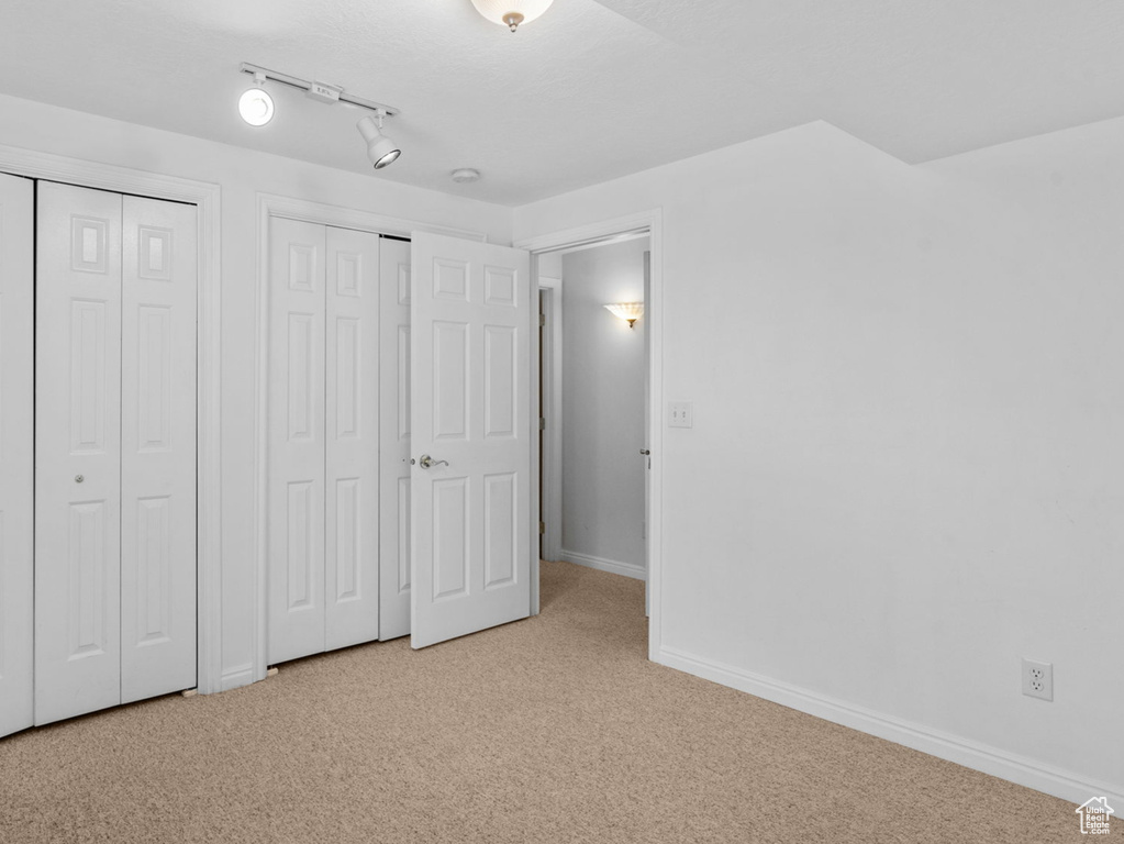 Unfurnished bedroom with carpet floors, multiple closets, and baseboards