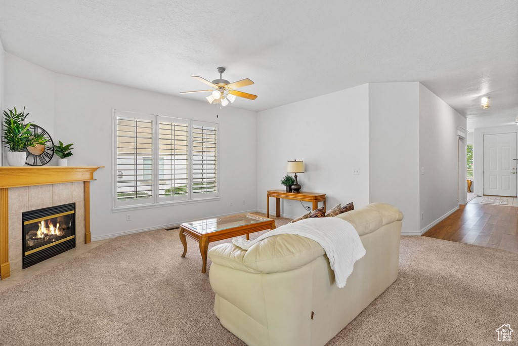 Living room with carpet, a ceiling fan, a fireplace, and baseboards