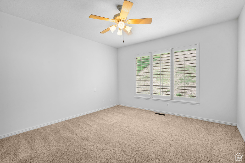 Spare room with carpet floors, a ceiling fan, and baseboards