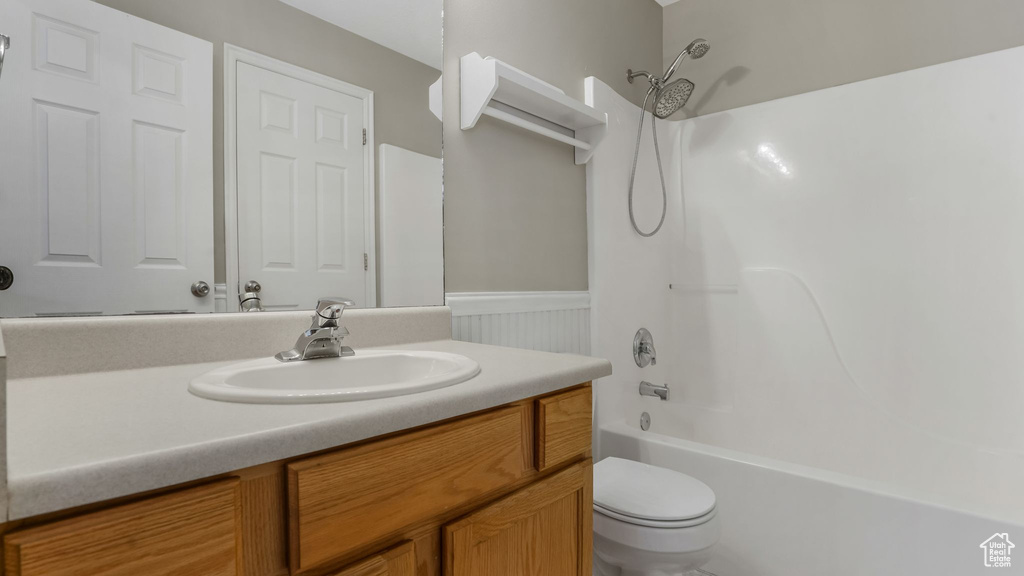 Full bath with wainscoting, vanity, toilet, and bathing tub / shower combination