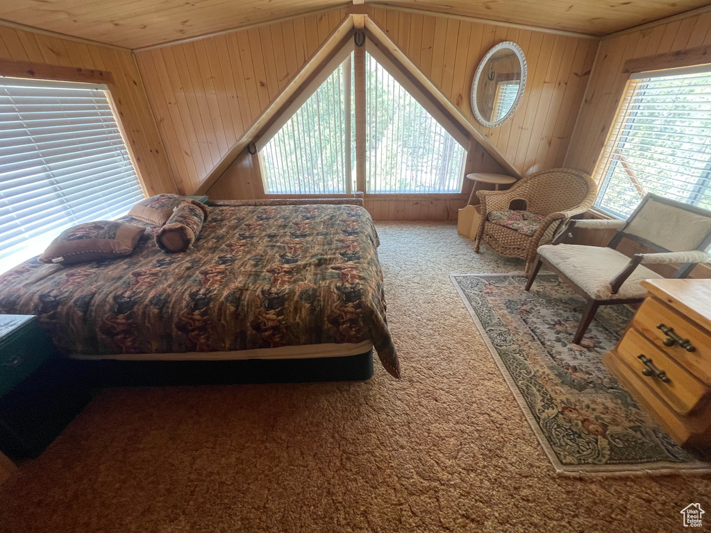 Bedroom with wooden ceiling, carpet, multiple windows, and wooden walls