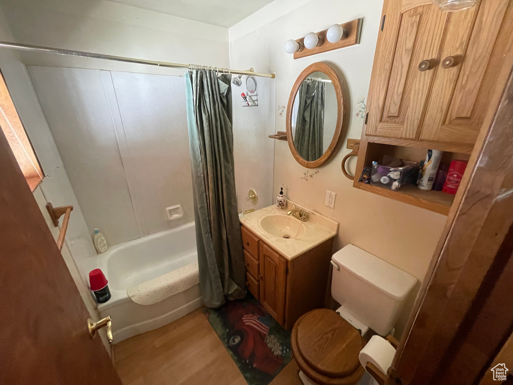 Bathroom with toilet, shower / tub combo with curtain, vanity, and wood finished floors