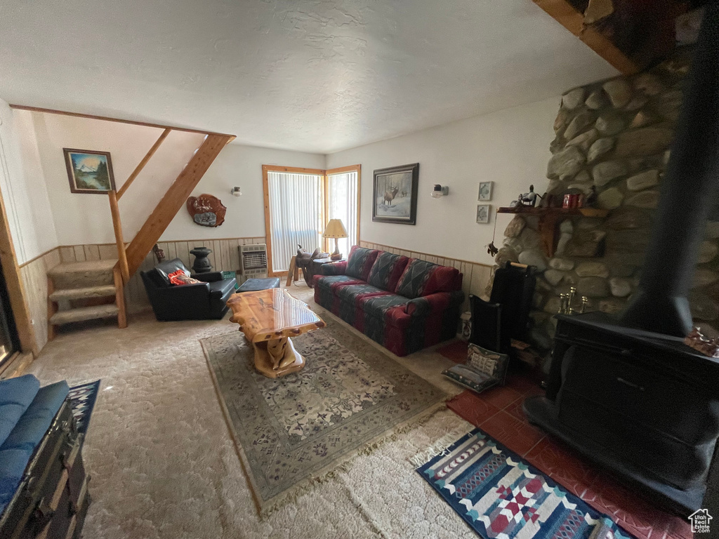 Carpeted living area featuring a wood stove, a wainscoted wall, and stairway