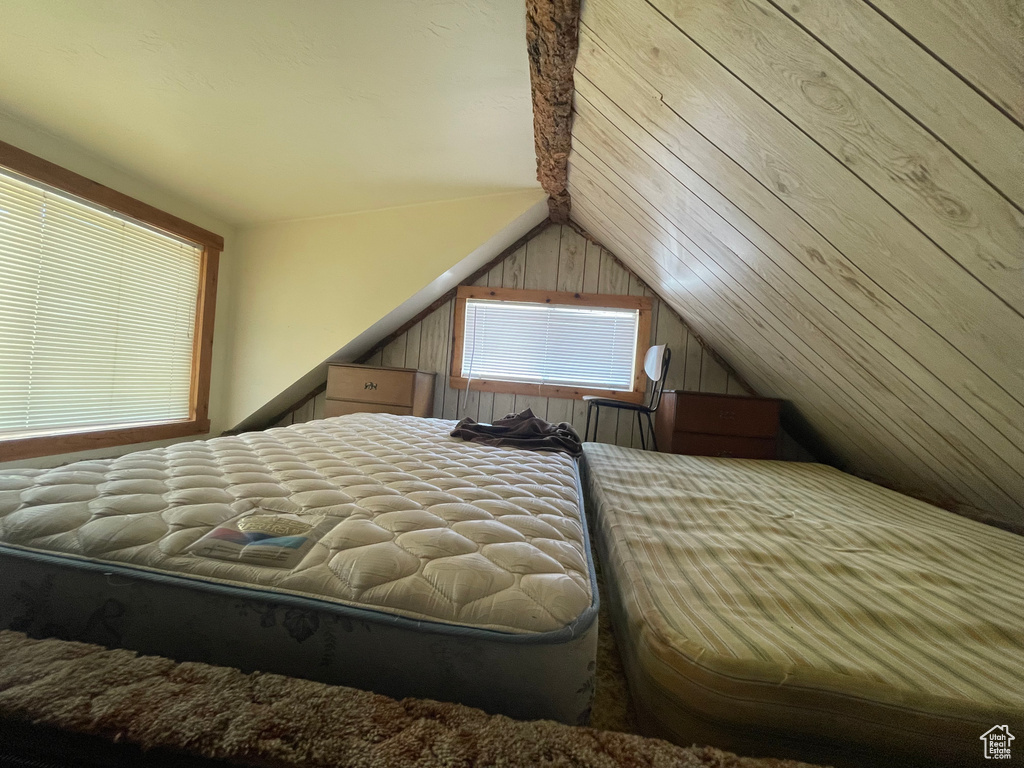 Bedroom featuring vaulted ceiling and wood walls