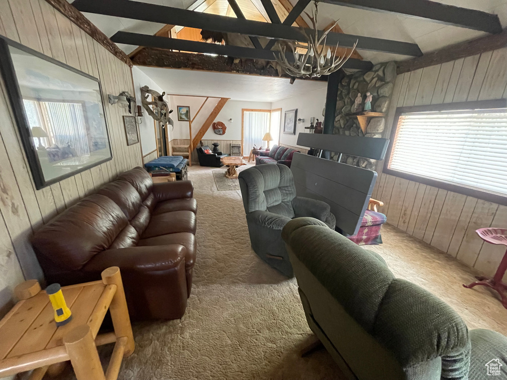 Carpeted living room with wooden walls, a chandelier, and stairway