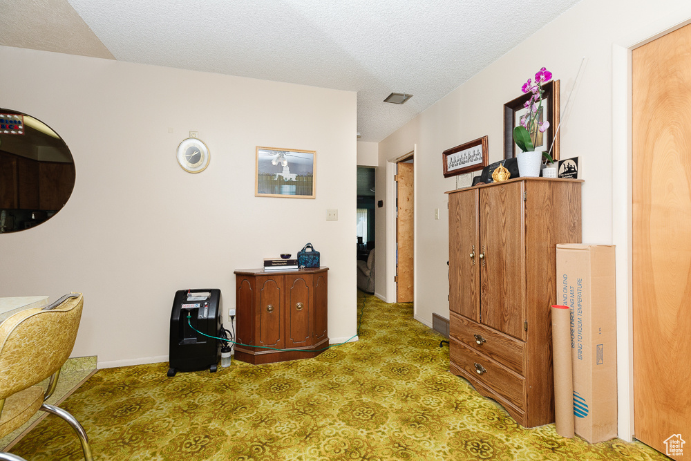 Carpeted home office featuring a textured ceiling
