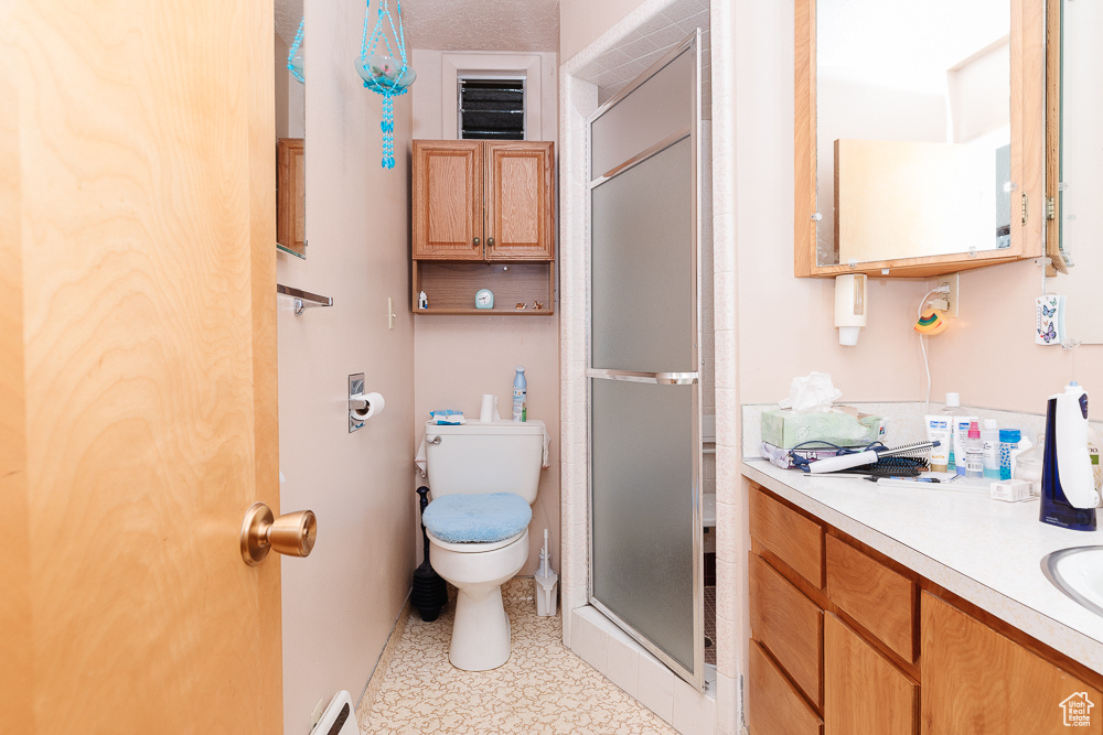 Full bathroom featuring toilet, a stall shower, vanity, and tile patterned floors