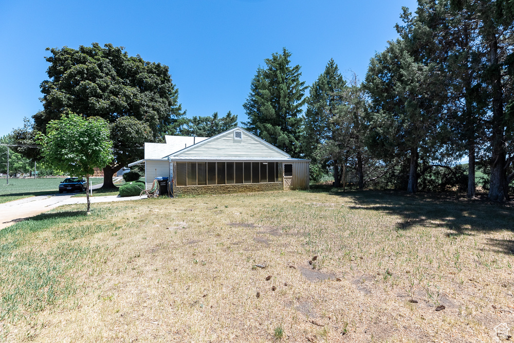 View of green lawn featuring a sunroom