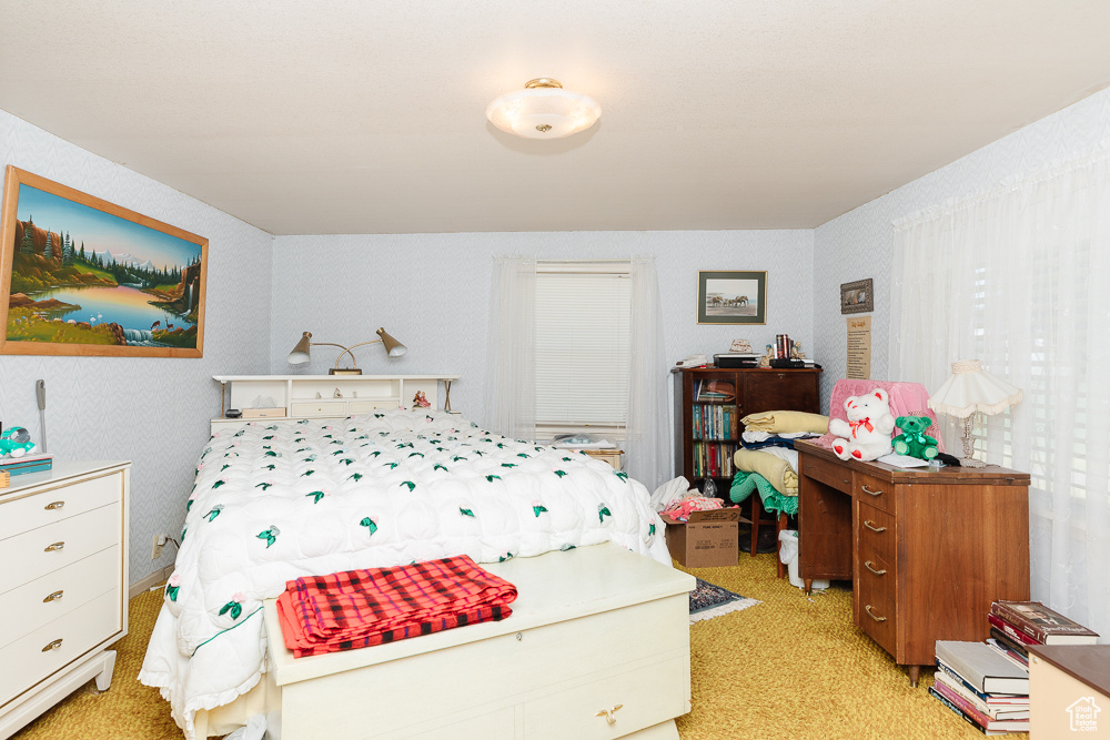 Bedroom with wallpapered walls and light colored carpet