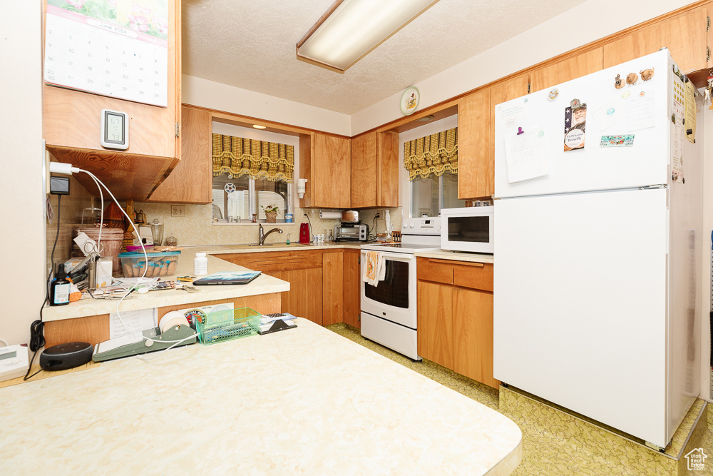 Kitchen featuring white appliances, light countertops, a sink, and a textured ceiling
