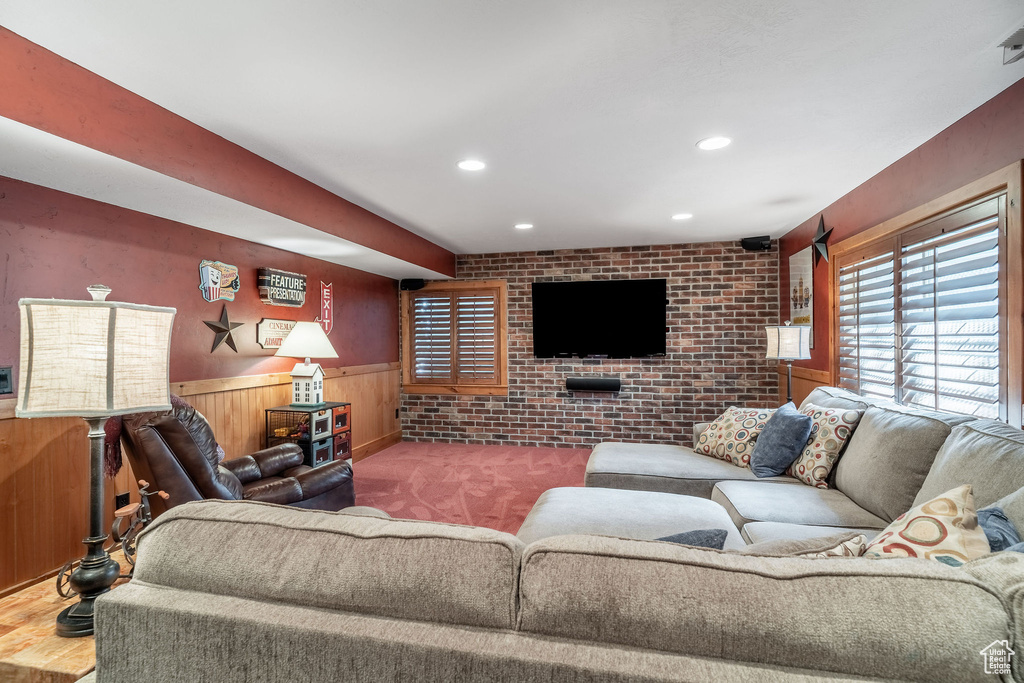 Living room featuring wainscoting, recessed lighting, wooden walls, brick wall, and carpet