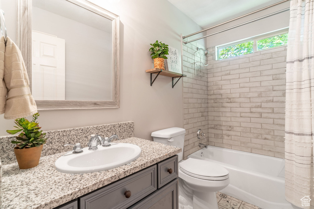 Bathroom with vanity, shower / bath combo, and toilet