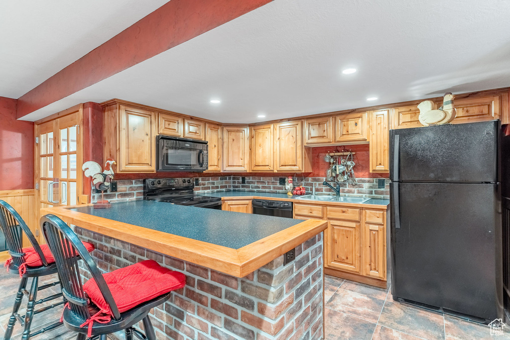 Kitchen with black appliances, a sink, tasteful backsplash, a peninsula, and a breakfast bar area
