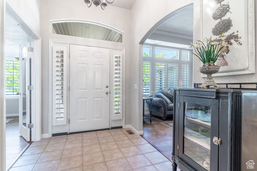 Foyer entrance featuring arched walkways, healthy amount of natural light, crown molding, and baseboards