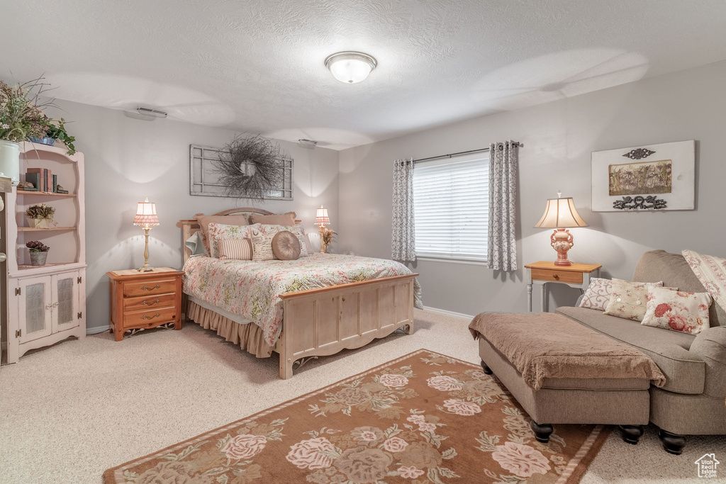 Bedroom with light colored carpet, baseboards, and a textured ceiling