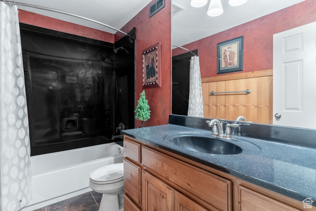 Bathroom featuring vanity, toilet, shower / bath combo with shower curtain, and wainscoting