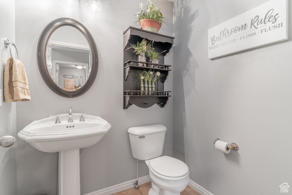 Half bathroom featuring toilet, baseboards, and tile patterned floors