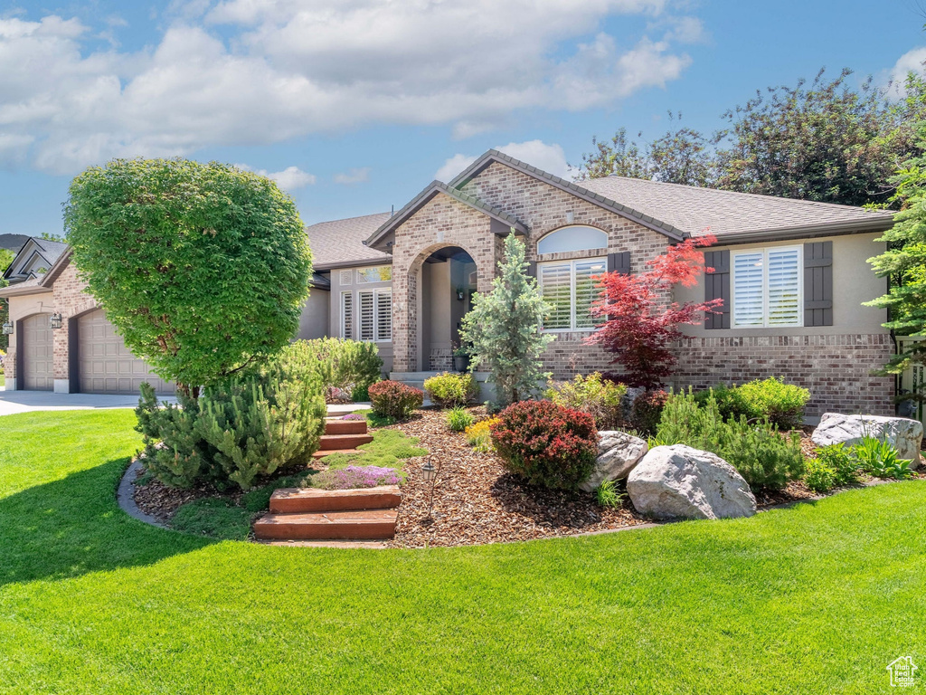 View of front facade with brick siding, concrete driveway, a front yard, and a garage