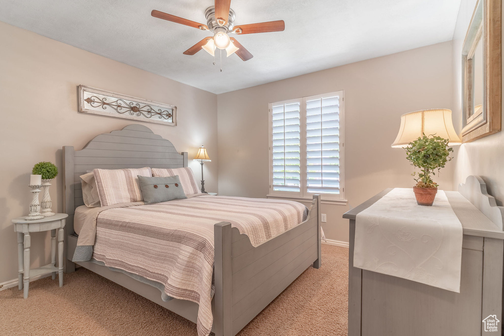 Bedroom featuring light carpet, baseboards, and a ceiling fan