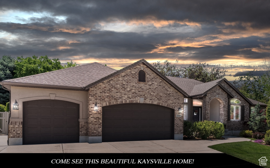 French provincial home with brick siding, an attached garage, concrete driveway, and roof with shingles