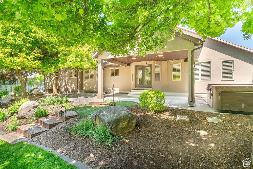 Back of property featuring french doors, stucco siding, a patio, and a hot tub