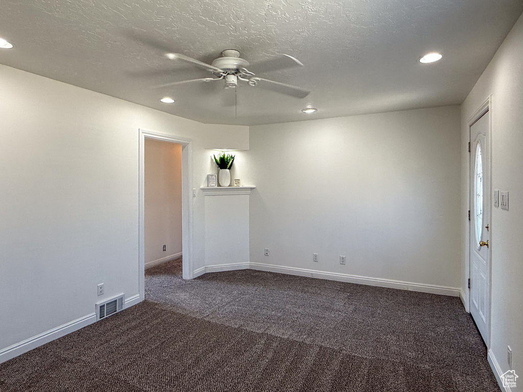 Empty room featuring recessed lighting, dark colored carpet, a ceiling fan, baseboards, and a textured ceiling