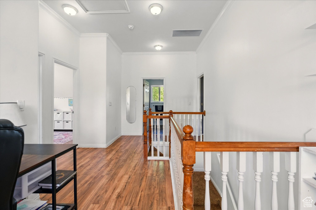 Hall with an upstairs landing, crown molding, wood finished floors, and baseboards
