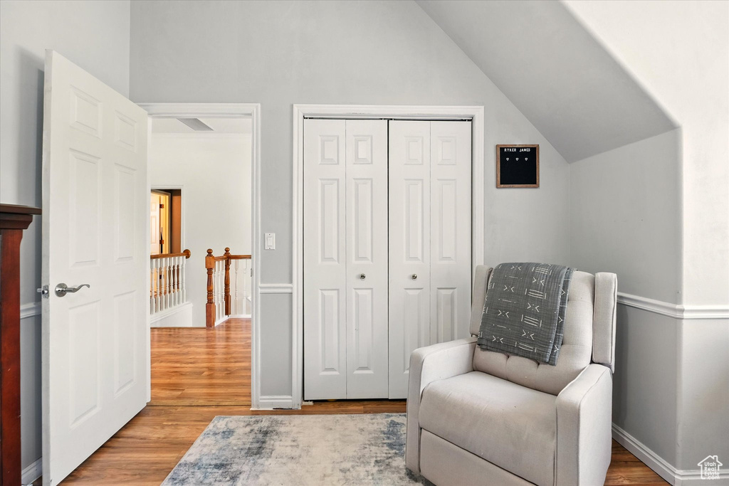 Sitting room featuring wood finished floors, lofted ceiling, an upstairs landing, and baseboards