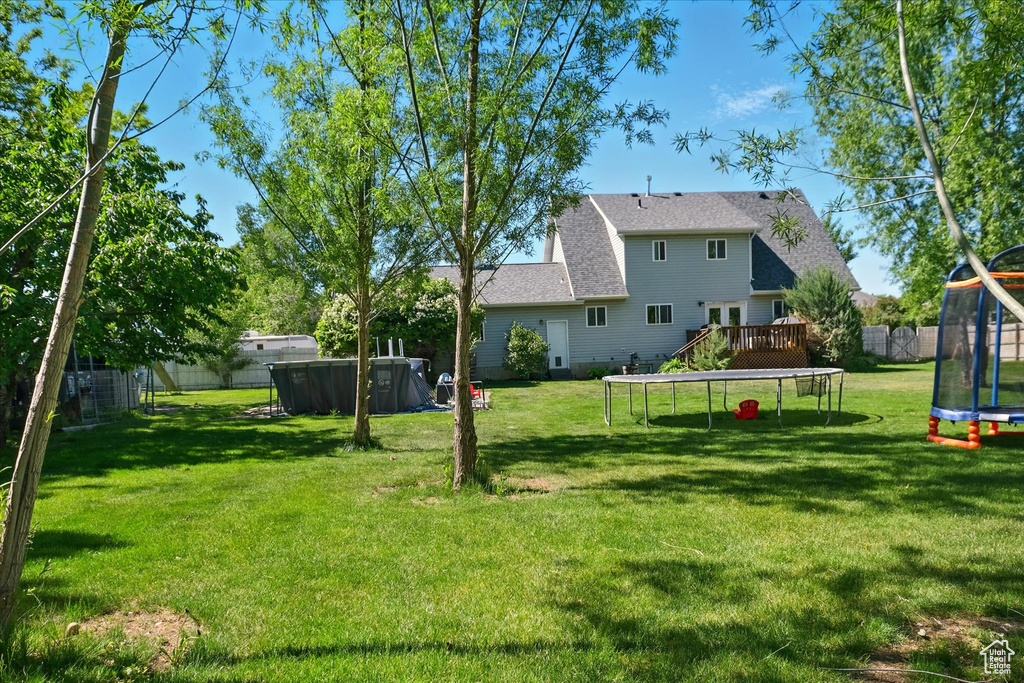 View of yard featuring a trampoline and a deck