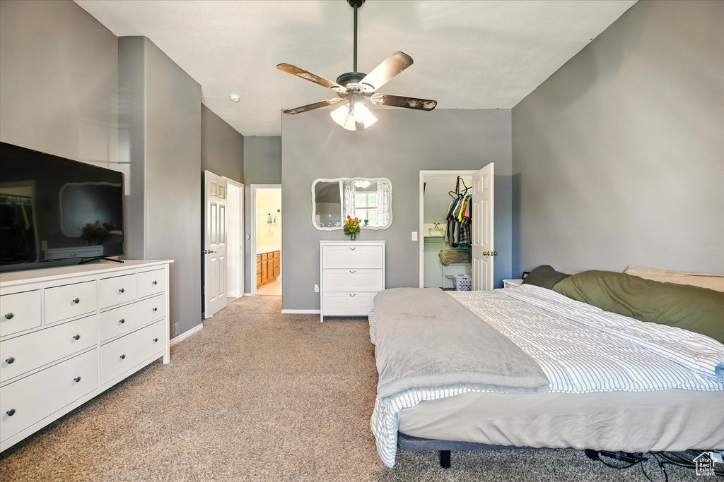 Bedroom featuring light colored carpet, a walk in closet, baseboards, a closet, and connected bathroom
